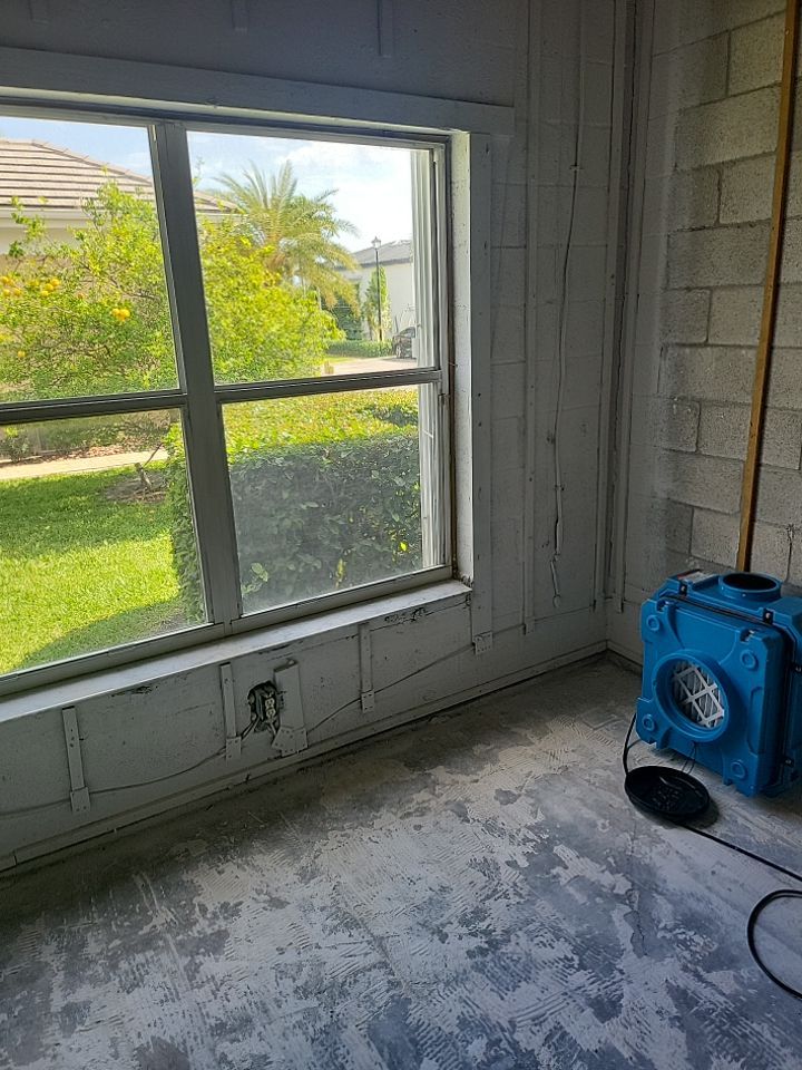Stripped block wall room with window and air scrubber after fire damage restoration